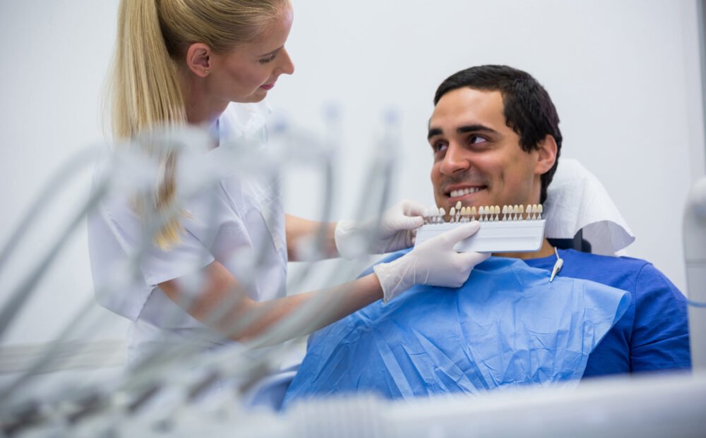 Dentist examining female patient with teeth shades at clinic